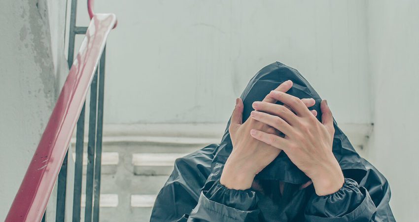 An upset young man wearing a hoodie and bowing his head