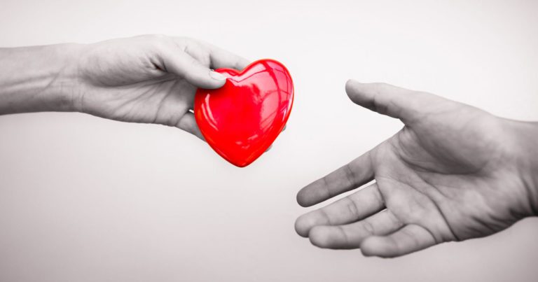 A person handing a plastic heart